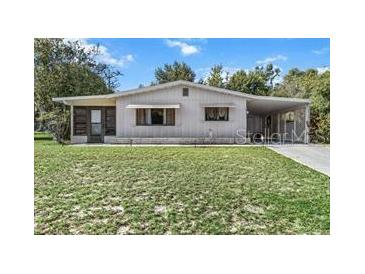 Charming single-story home with covered carport and well-maintained lawn, nestled among mature trees at 8954 Sw 104Th Ln, Ocala, FL 34481