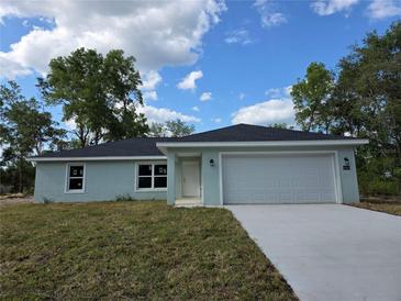 Charming single-story home with a well-manicured lawn and a two-car garage, perfect for suburban living at 10435 Se 125 Ln, Belleview, FL 34420