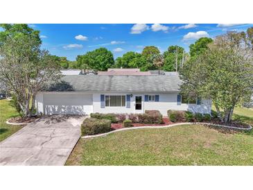 Charming home featuring blue shutters, a well-manicured lawn, mature landscaping, and an attached two-car garage at 11118 Sw 76Th Ave, Ocala, FL 34476