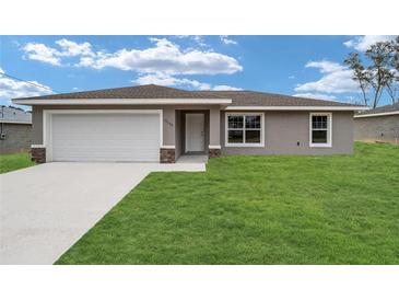 Charming single-story home with a well-manicured lawn and attached two-car garage at 11887 Se 71St Ave, Belleview, FL 34420