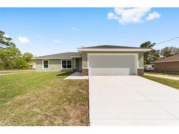 Charming single-story home featuring a well-manicured lawn and a spacious two-car garage at 207 Juniper Loop Cir, Ocala, FL 34480