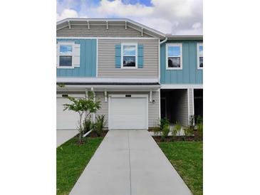 Two-story townhome featuring a one-car garage, charming blue shutters, and fresh landscaping at 3571 Se 37Th Ct, Ocala, FL 34480