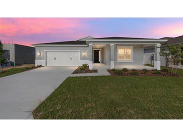 Charming single-story home featuring a two-car garage, covered porch, and well-manicured lawn at dusk at 5714 Sw 75Th Ave, Ocala, FL 34474