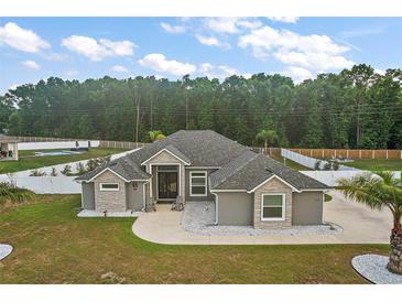 Stunning gray home with a well-manicured lawn and a spacious driveway, plus a fenced backyard with a pool at 6292 Se 13Th St, Ocala, FL 34472