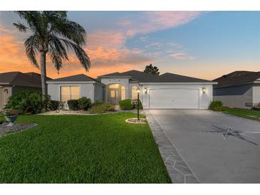 Charming single-story home with manicured lawn, mature palm tree, and two-car garage, bathed in the warm glow of sunset at 680 Farmington Ave, The Villages, FL 32162