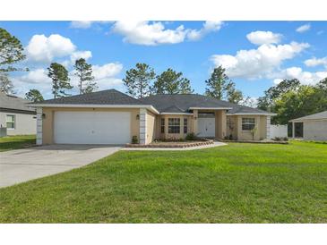 Charming single-story home with a well-manicured lawn, inviting entrance, and two car garage at 7370 Sw 129Th Ln, Ocala, FL 34473
