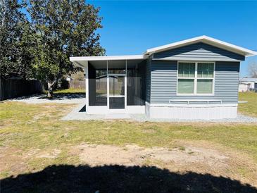 Charming home exterior with blue siding, screened porch, and well-maintained lawn on a sunny day at 9247 Se 142Nd Pl, Summerfield, FL 34491