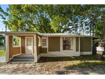 Charming single-story home with brown siding, a covered porch, and a mature tree in the front yard at 935 Ne Sanchez Ave, Ocala, FL 34470