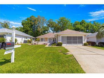 Charming home featuring a well-manicured lawn and a convenient screened-in two-car garage at 11058 Sw 69Th Cir, Ocala, FL 34476