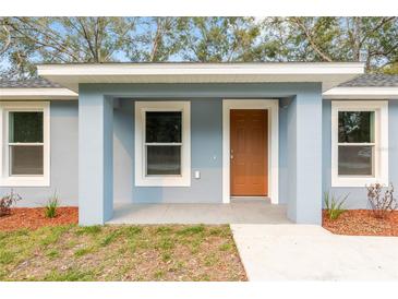 Charming front porch of a home with a brown front door and fresh landscaping at 13300 Sw 105Th Pl, Dunnellon, FL 34432