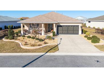 Charming home featuring manicured landscaping, a covered front porch, and a two-car garage at 8878 Sw 103Rd Cir, Ocala, FL 34481
