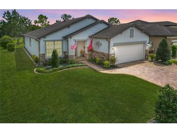 Charming home with a well-manicured lawn, beautiful landscaping, and a brick paver driveway at 9740 Sw 68Th Ln, Ocala, FL 34481