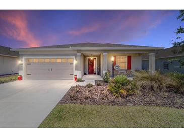 Charming home featuring a well-maintained front yard, two-car garage and a welcoming front porch at 10033 Sw 96Th St, Ocala, FL 34481
