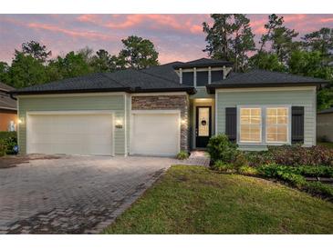 Charming single-Gathering home featuring a two-car garage, well-manicured lawn, and stone architectural details at 1119 Se 42Nd Rd, Ocala, FL 34480