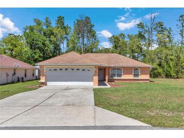 Charming single-story home features a two-car garage and well-maintained front yard with mature trees at 13173 Sw 65Th Cir, Ocala, FL 34473