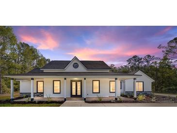 Beautiful single-story home featuring a covered porch and landscaped front yard against a stunning sunset backdrop at 14115 Nw 141St Ave, Williston, FL 32696