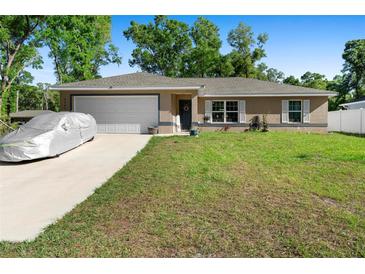 Charming single story home with a well-maintained lawn and a covered car in the driveway at 4243 Se 131St Ln, Belleview, FL 34420