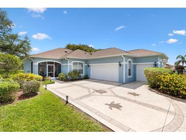Charming single-story home with a light blue exterior, decorative driveway, and well-maintained landscaping at 17536 Se 119Th Cir, Summerfield, FL 34491
