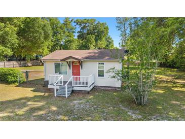 Charming home featuring a bright red front door, cozy porch, and well-maintained lawn at 2300 Ne 49Th St, Ocala, FL 34479