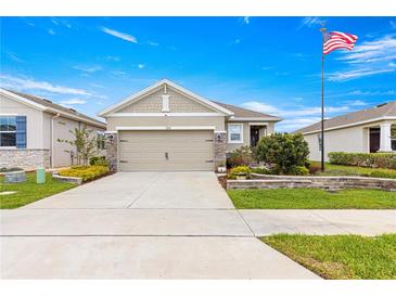 Charming home featuring a well-manicured lawn, a two-car garage, and an American flag at 5220 Sunshine Dr, Wildwood, FL 34785