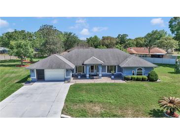 Aerial view of light blue one-story home, with a manicured green lawn and a two car garage at 5350 Sw 82Nd St, Ocala, FL 34476