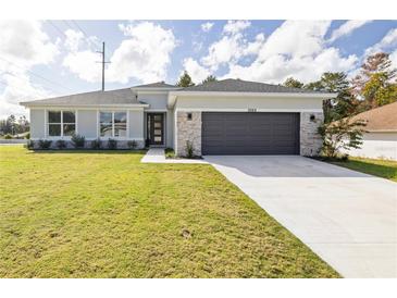 Charming single-story home featuring a two-car garage, stone accents, and a well-manicured lawn at 7082 Sw 128 Place E Rd, Ocala, FL 34473