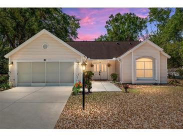 Charming one-story home featuring a two-car garage, a manicured lawn, and a cozy front porch at sunset at 712 Harper Pl, Lady Lake, FL 32159