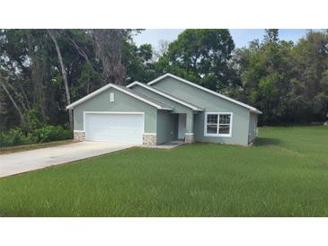 Charming single Gathering home featuring a two car garage, stone accents, and a well manicured lawn at 8661 Juniper Rd, Ocala, FL 34480