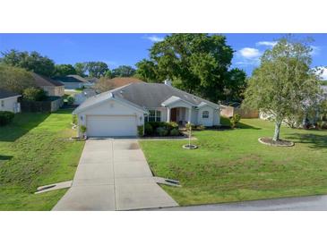 Traditional single-story home featuring an attached garage and well-maintained lawn at 8895 Sw 57Th Court Rd, Ocala, FL 34476