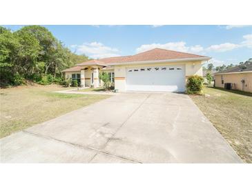 Spacious single-story home with a wide driveway and two-car garage, set against a backdrop of trees at 2730 Sw 162Nd Street Rd, Ocala, FL 34473