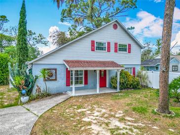 Charming two-story home featuring a covered front porch, vibrant red shutters, and lush landscaping at 6403 Summit Dr, Orlando, FL 32810