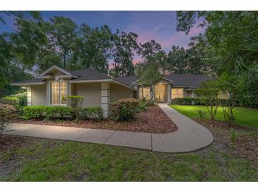 Charming single-story home with manicured lawn and inviting walkway, surrounded by mature trees and lush landscaping at 733 Se 67Th Ln, Ocala, FL 34480