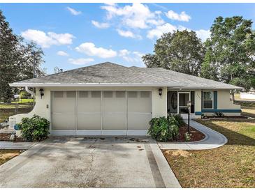 Charming one-story home with a well-manicured lawn, mature shrubbery, and an attached two-car garage at 8990 Se 155Th Pl, Summerfield, FL 34491