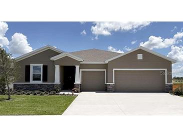 Charming single-story home features a two-car garage, stone accents, and manicured lawn at 3053 Canopy Oak Blvd, Wildwood, FL 34785