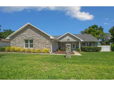 Charming single-story home featuring a stone facade, lush green lawn, and well-manicured landscaping at 4401 Sw 44Th Ln, Ocala, FL 34474