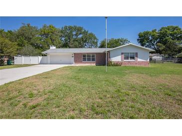 Charming single-story home with an attached garage, stone accents, and a well-manicured lawn at 4810 County Road 114, Wildwood, FL 34785