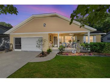Dusk view of a charming home featuring a covered front porch, attached garage, and lush lawn at 9153 Sw 83Rd Ter # E, Ocala, FL 34481