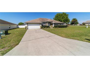Inviting single-story home featuring a well-maintained lawn, mature shrubbery, and a convenient two-car garage at 9896 Sw 56Th Ct, Ocala, FL 34476