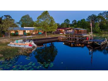 Beautiful waterfront home featuring two houses with a large dock and an inviting pontoon boat at 23800 Ne 190Th St, Fort Mc Coy, FL 32134