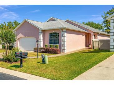 Charming single-story pink home with manicured lawn, white trim, and attached garage on a sunny day at 2935 Sw 41St Pl, Ocala, FL 34474