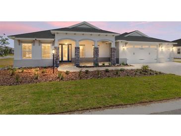 Charming single-story home showcasing stone-accented columns and well-manicured front yard at 9973 Sw 107Th Ter, Ocala, FL 34481