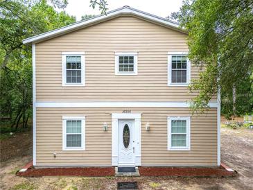 Charming two-story home featuring light beige siding, a white door with glass insert, and matching trim at 16295 W Highway 40, Ocala, FL 34481