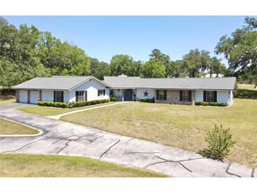 Sprawling ranch home with brick and white accents surrounded by lush greenery at 1711 Sw 63Rd St Rd, Ocala, FL 34476