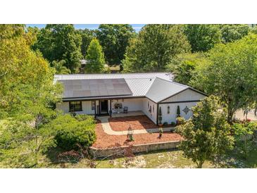 Beautiful home featuring solar panels, a metal roof, and meticulously landscaped grounds, blending comfort and efficiency at 18695 Ne 5Th Terrace Rd, Citra, FL 32113