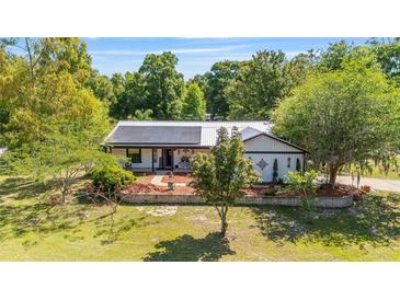 Charming home with a metal roof and solar panels, complemented by a well-manicured lawn and lovely landscaping at 18695 Ne 5Th Terrace Rd, Citra, FL 32113