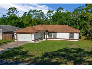 Charming one-story home with a well-maintained lawn and attached two-car garage at 2312 Sw 140Th Ct, Ocala, FL 34481
