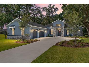 Charming home featuring a manicured lawn, stone accents, a two-car garage, and a welcoming front entrance at 2515 Se 77Th St, Ocala, FL 34480
