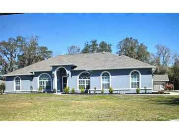 Charming single-story home featuring a well-manicured lawn, arched windows, and neutral exterior paint at 5281 Sw 33Rd St, Ocala, FL 34474