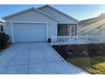 Charming single-story home with a two car garage, white picket fence, and well manicured landscaping at 627 Vagabond St, The Villages, FL 32163