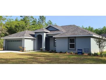 Beautiful single-story home with a gray exterior, complemented by lush landscaping and a well-manicured lawn at 8725 Sw 136Th Ter, Dunnellon, FL 34432
